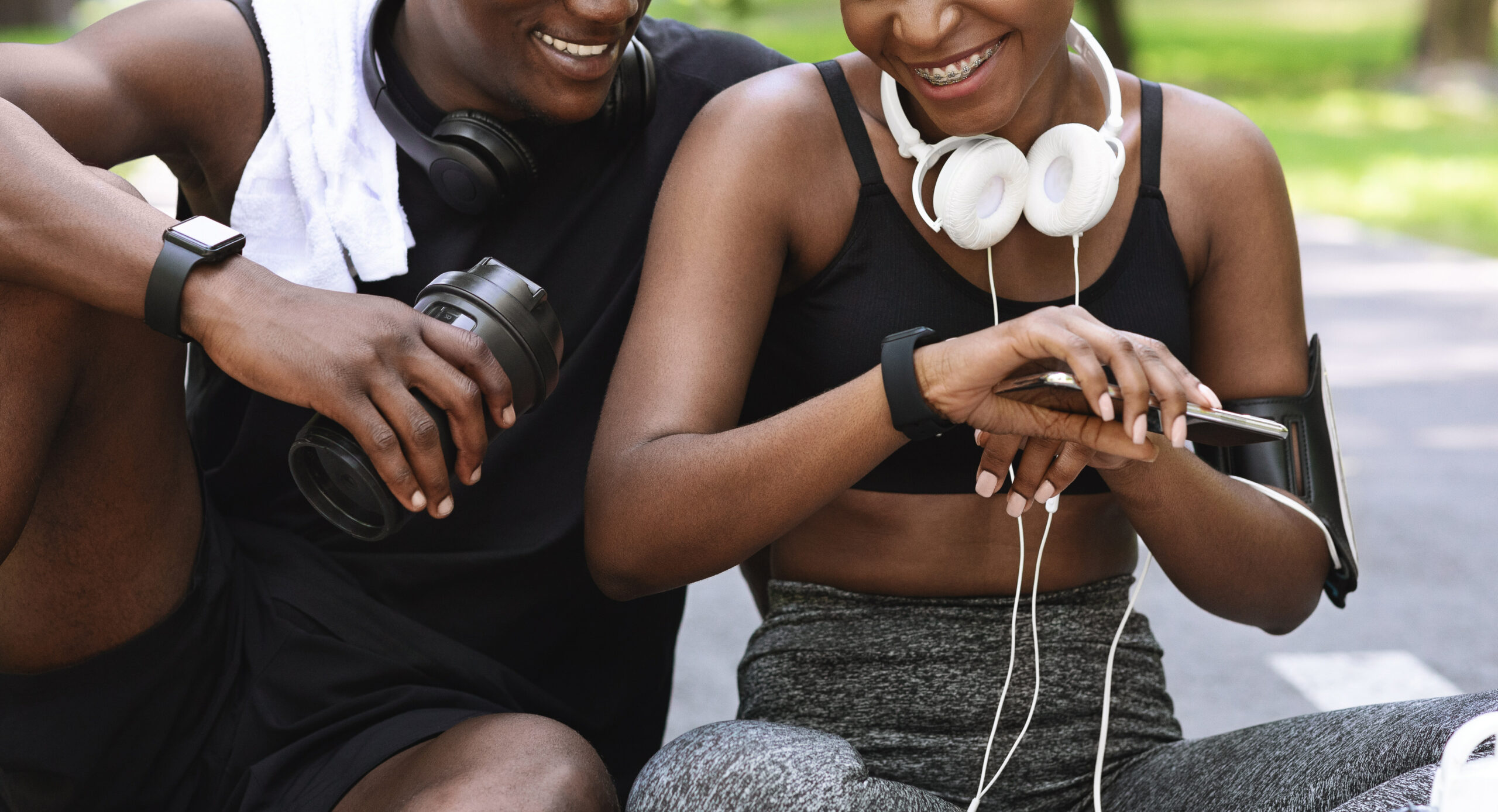 Sport Gadgets. Black Athlete Couple Using Smartwatch Outdoors For Tracking Fitness Activity, Closeup