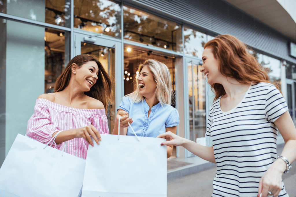 Three girls laugh together while shopping.
