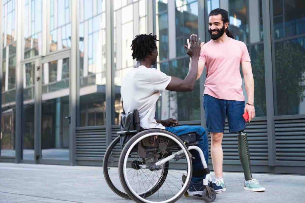 A pair of disabled friends on vacation having fun and breaking down barriers. They share a moment of joy high fiving each other in celebration of their friendship.